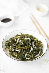 seaweed salad with onion and soy sauce in a white plate