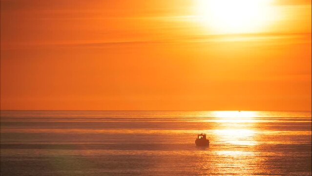 Seascape, sun rising above horizon. Fishing boat on sea water at sunrise orange color light. Nature landscape, early morning. Timelaspe