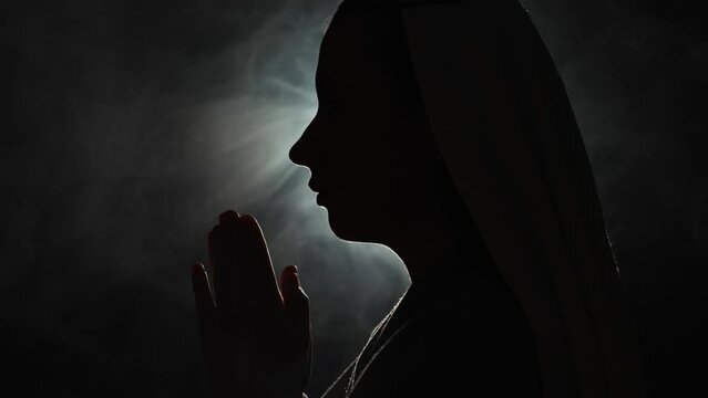 Nun praying in a dark place