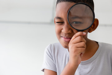 Smiling kid boy playing cheerfully with magnifying glass