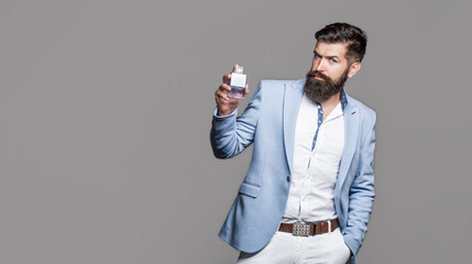 Fototapeta premium Perfume or cologne bottle and perfumery, cosmetics, scent cologne bottle, male holding cologne. Masculine perfume, bearded man in a suit. Copy space. Masculine perfume, bearded man in a suit