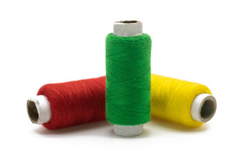 yellow, green and red color yarn or spool thread over on white background, front view