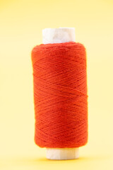 single red color yarn or spool thread over on yellow background