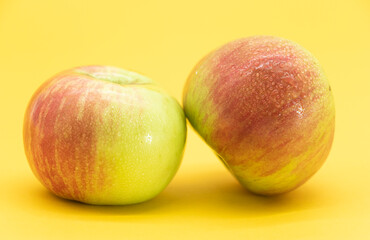 two fresh apple with drop of water isolate on yellow background