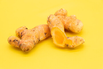 raw turmeric root slices isolated on yellow background