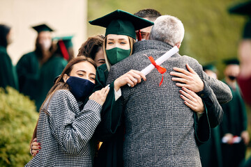 Happy graduate hugs with her family after receiving university diploma during coronavirus pandemic.