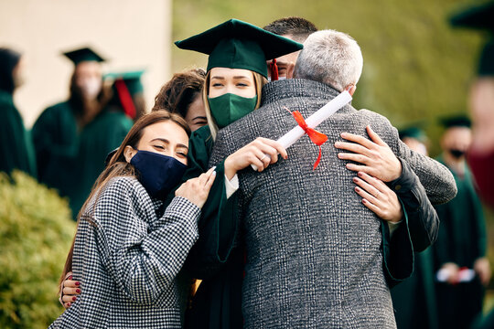 Happy Graduate Hugs With Her Family After Receiving University Diploma During Coronavirus Pandemic.