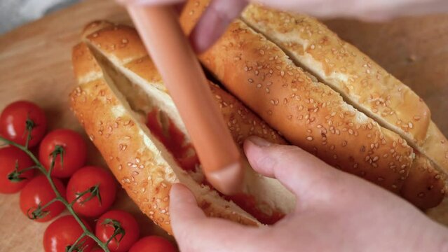female hands of the cook put the sausage in the bun. The process of making a hot dog at home.