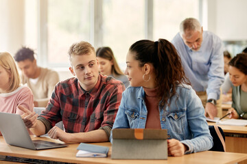 College classmates collaborate while e-learning during class at lecture hall.