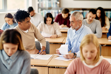 Fototapeta premium African American student talks to his teacher during a class at university.