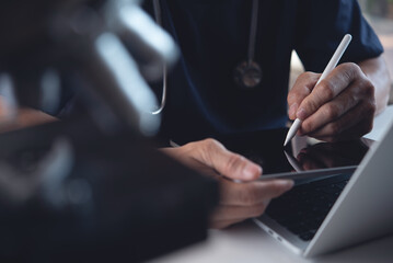 Doctor using digital tablet and working on laptop computer with microscope. Medical student or technician recording lab test on tablet pc in hospital laboratory