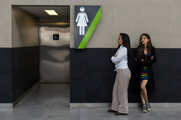 Two adult Latin American women mother and daughter urgently waiting in line to enter public...