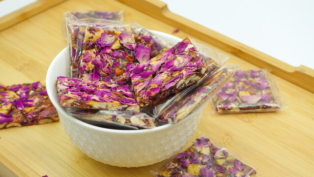 Rose Chikki. Rose petals wrapped around tasty peanuts chiki. Popular Indian festive sweet from India. Peanut Jaggery chikki made using groundnut or shengdana.