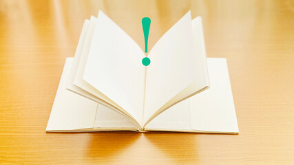 テーブルの上で開いた本とびっくりマーク