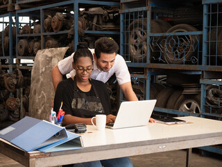 African saleswoman recommends automotive spare parts for a customer from a tablet computer in warehouse automotive parts.