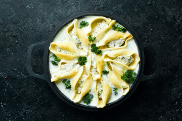Pasta stuffed with turkey meat, cream sauce and parmesan. In a frying pan. Italian traditional cuisine. Recipe.