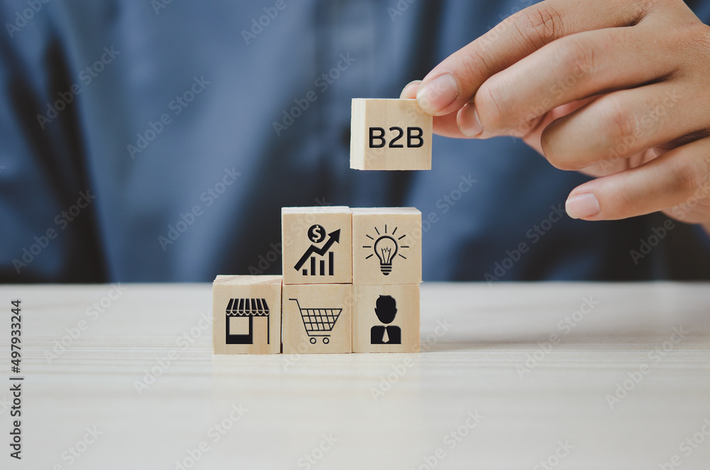Poster hand put wooden cubes with b2b business to business icons and symbols on table and copy space.busine