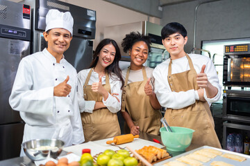 Cooking  course , senior Asian male chef in cook uniform teaches young asian and african american people cooking class students to prepare, mix ingredients for pastry foods, in restaurant stainless 