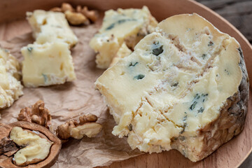 Danish blue cheese. Tasty blue cheese on a wooden background and burlap. Dorblu cheese pieces. Food recipe background. Close up
