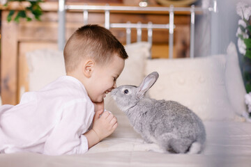 cute cheerful boy is playing with a rabbit. Easter card. Christian traditions. Fun, laughter and positive. Child and pet. Little farmer. Country mood. Best friends with animals. Hare in a basket