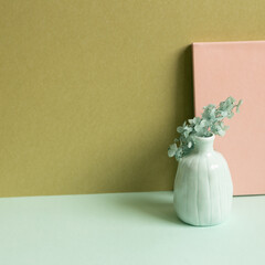 Pink notebook and vase of dry hydrangea flower on sky blue desk. khaki wall background