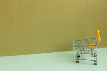 Shopping cart on sky blue and khaki background. Business concept