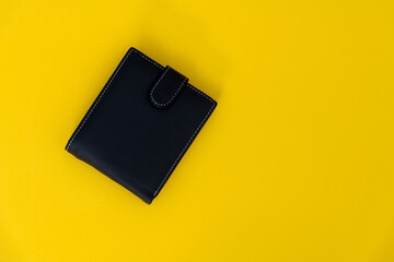 Black leather wallet on yellow background