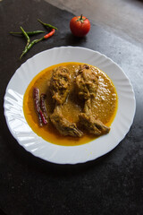 Indian mughal dish chicken chap prepared with big pieces of chicken meat in rich spicy gravy served in a white plate. Top view.