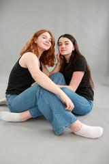 two beautiful girls on a gray background. girlfriends hugging. red hair color. studio photo shoot. female friendship. stop the war