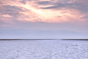 Obraz premium Salt flats in Death Valley at sunset. Mountains are hidden in haze