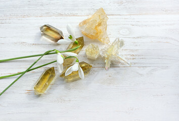 gemstones and spring snowdrops flowers on white wooden background. minerals for esoteric spiritual...
