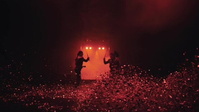 sword fight in the circus arena with beautiful red lighting in the fog, flying confetti, slow motion, 2 warriors fighting with swords, fencing, staged fight