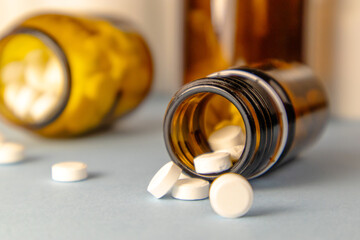 White pills falling out of glass drug bottle. Vitamins or medicine concept.