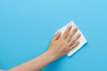 Hand holding paper towel for cleaning on blue background
