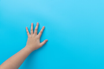 Children's hand on a blue wall