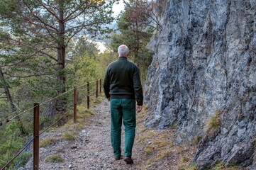 A mountain hiker walks  a narrow, steep serpentine path on the Sass mountain in Tyrol, downhill into the Inn Valley.