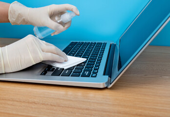 Woman hand cleaning laptop with napkin