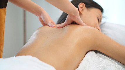 Close up masseur hands doing back massage with oil in the beauty spa. Woman lying down on the spa bed. Relaxing or revitalizing of muscle after work. Enjoying full body care. Healthy and spa concept