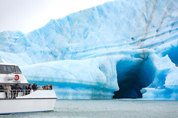 Escursione in barca  di un gruppo di turisti per ammirare un iceberg in Patagonia  - obrazy, fototapety, plakaty