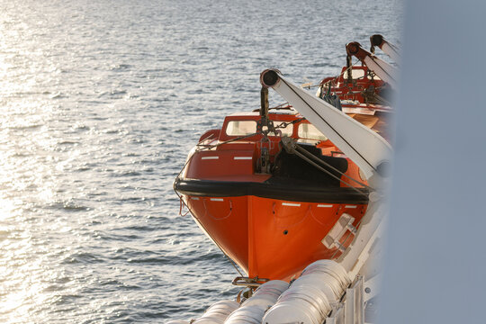 Orange lifeboat on side of north sea ferry boat crossing channel to France or Holland for passengers to escape sinking ship. Emergency life preserve