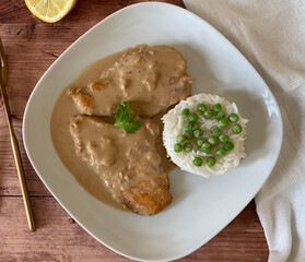 Austrian chicken schnitzel naturally fried with sauce, rice and peas.