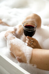 Girl holding a glass of wine in her hand enjoying a bubble bath with her boyfriend