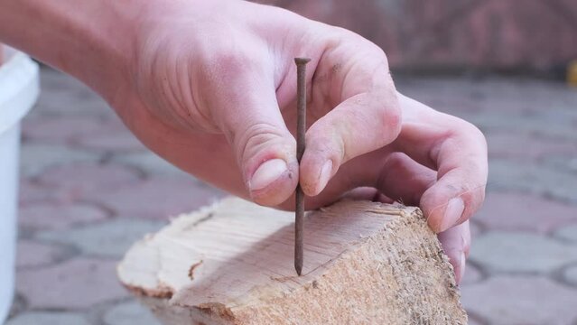 Male hand hammers a rusty nail