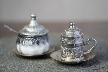 Silver coffee cup and silver sugar jars.close up.