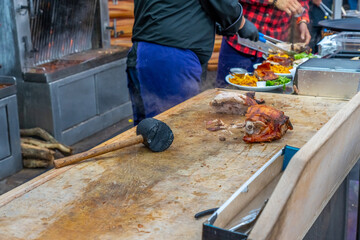 Street grill, fried meat. A man cuts a fried piece of meat into portion. Traditional christmas street food fair in Monaco.