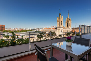 Terrace in a penthouse apartment with glass and metal dining table and views of the church of los jeronimos in Madrid