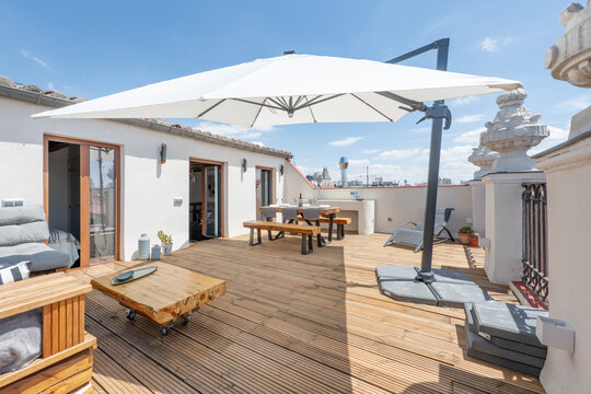 Terrace with a large parasol awning with wooden floors, dining table with wooden benches and solid wood