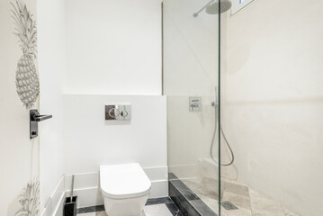 Modern toilet with black and white marble floors and shower cabin with glass partition