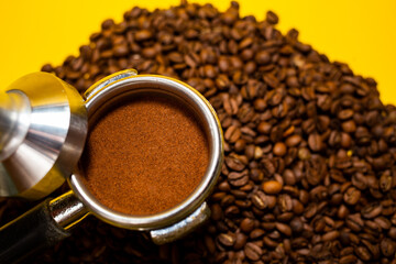 An open bag of fresh coffee beans. Holder filter with ground coffee for coffee machines. Selective focus. Close up.