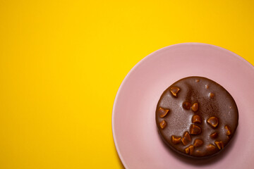 Chocolate tart on a pink plate. Yellow background, top view